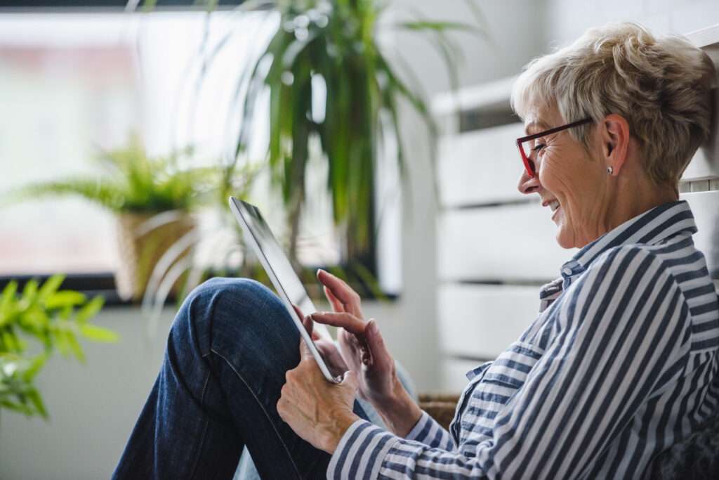 A smiling woman reading her wellness insights on a tablet at home